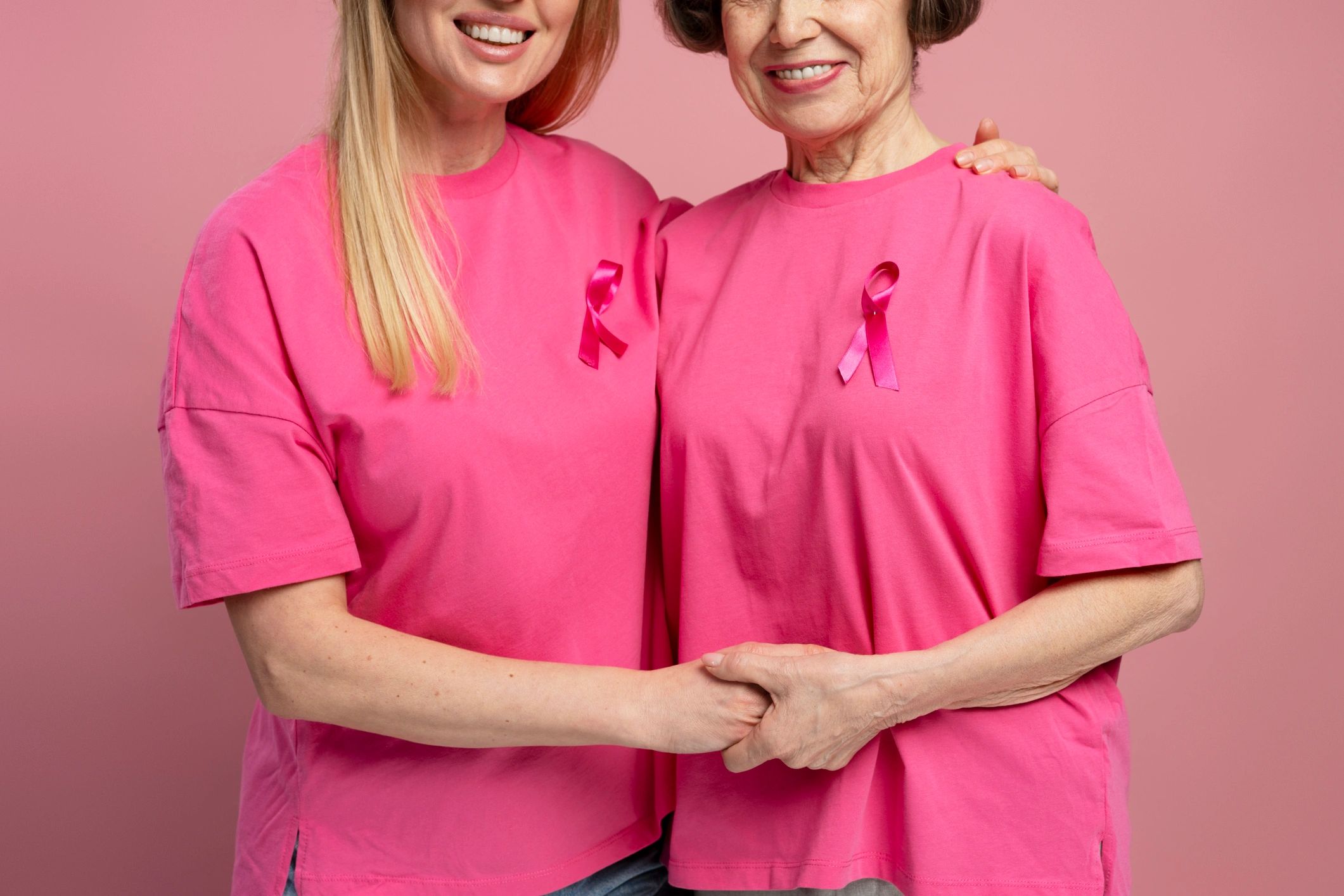Women holding hands and wearing pink ribbon for breast cancer awareness